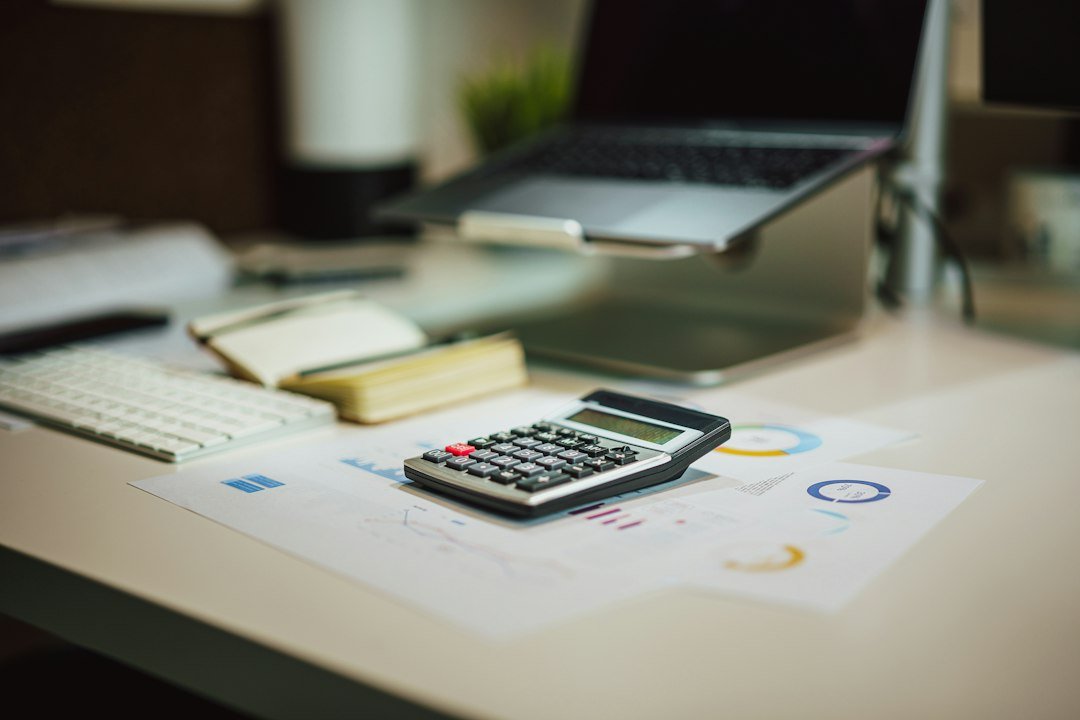 Calculator, notebook and laptop on a desk with financial reports
